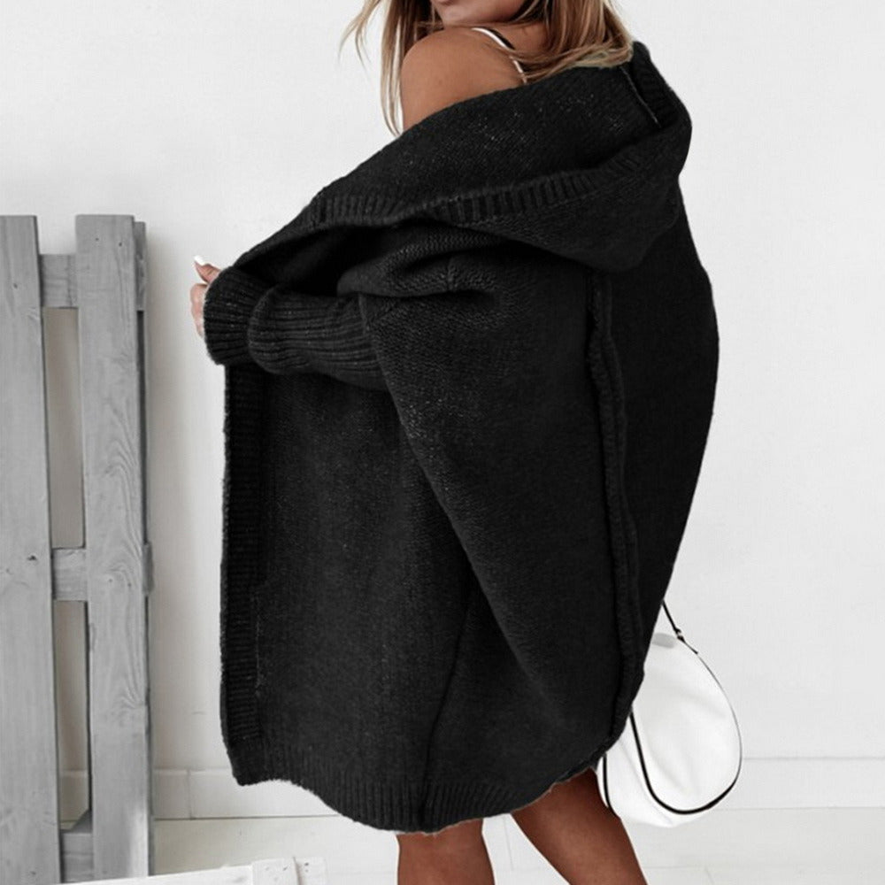 Frau in schwarzem Strick-Cardigan mit Kapuze, modisch und lässig, vor weißem Hintergrund. Perfekt für Herbstmode und gemütliche Outfits.
