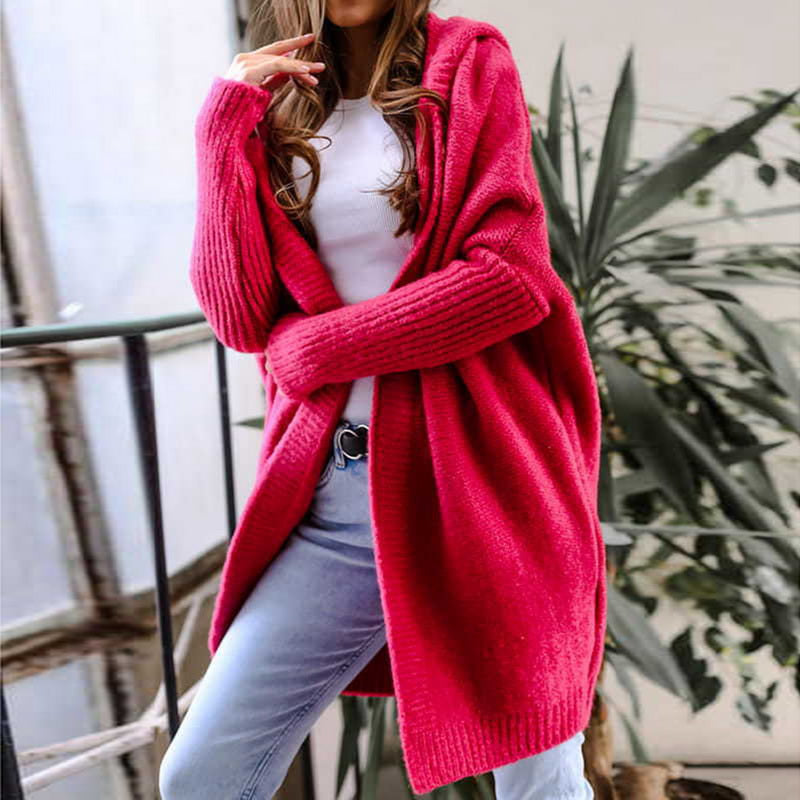 Frau in rotem Strickcardigan, weißem T-Shirt und blauer Jeans posiert lässig. Modetrend, Herbstmode, gemütlicher Look, Damenbekleidung.