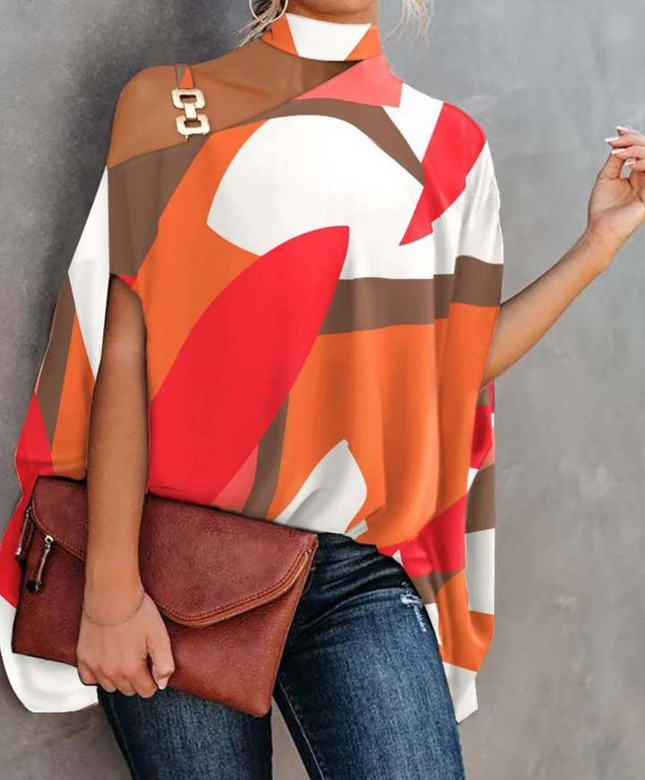 Frau in bunter, abstrakter Tunika mit geometrischem Muster, hält braune Lederhandtasche. Modetrend, Damenmode, stilvolles Outfit.