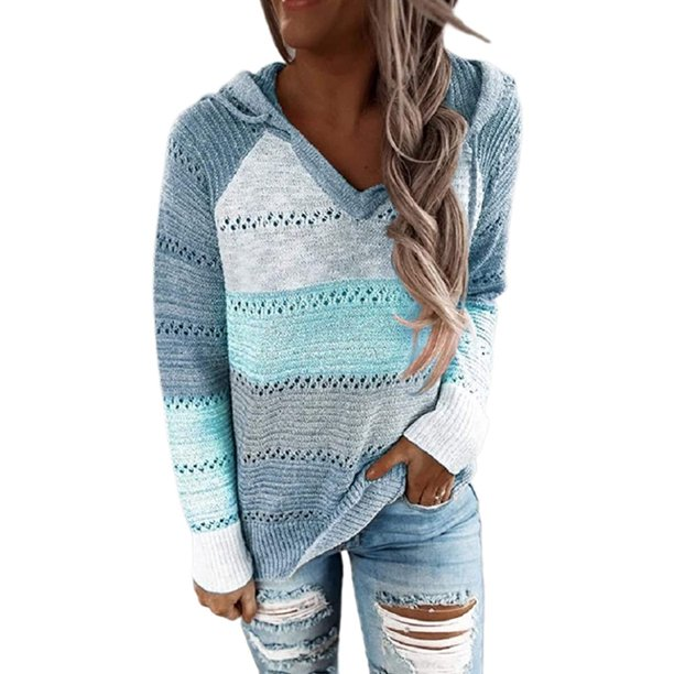 Frau in blau-weißem Strickpullover mit Kapuze und V-Ausschnitt, kombiniert mit zerrissenen Jeans. Modischer Freizeitlook für Damen.