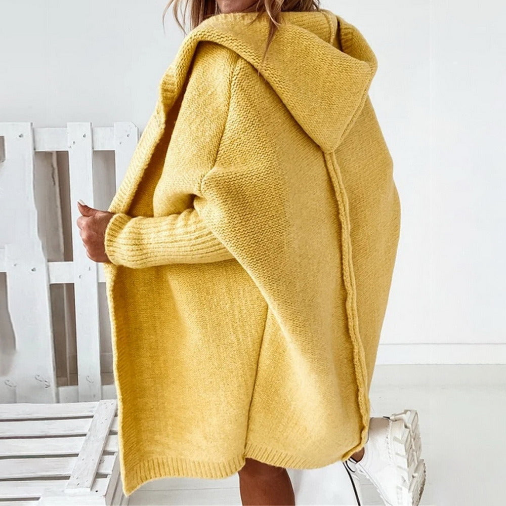 Gelber Strick-Cardigan mit Kapuze, lässig über die Schultern getragen. Modetrend Herbst/Winter, gemütlicher Oversize-Look, Damenmode.