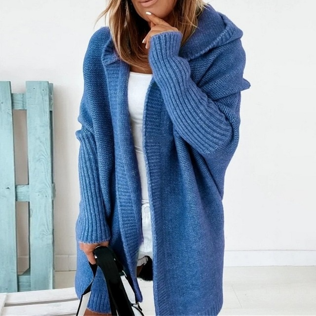 Frau in blauem Strickmantel, hält schwarze Tasche. Modischer, bequemer Damen-Cardigan, ideal für Herbst und Winter. Eleganter Freizeitlook.