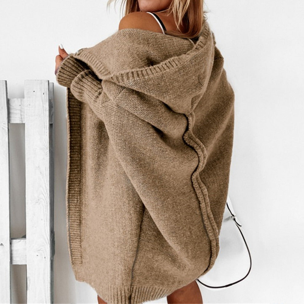 Frau in beigem Strickcardigan, Rückenansicht, vor weißem Hintergrund. Modischer Oversize-Pullover, Herbst-Winter-Trend, gemütlicher Look.