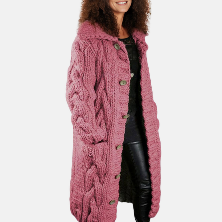 Frau in rosa Strickmantel mit Zopfmuster, große Knöpfe, lächelt, lockiges Haar. Modetrend, Wintermode, Damenbekleidung, stilvoller Mantel.