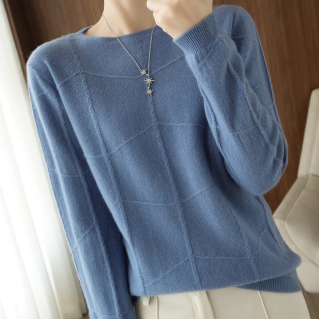 Dame in blauem Kaschmirpullover mit Karomuster, trägt eine Sternenhalskette. Elegante Herbstmode, gemütlicher Strick, stilvoller Look.