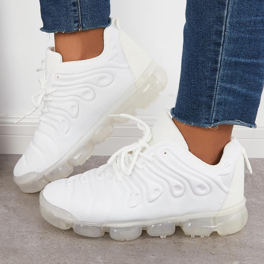 Weiße Sneaker mit transparenten Sohlen, getragen von Person in blauen Jeans. Moderne Sportschuhe, modisch, bequem, ideal für Freizeit und Sport.