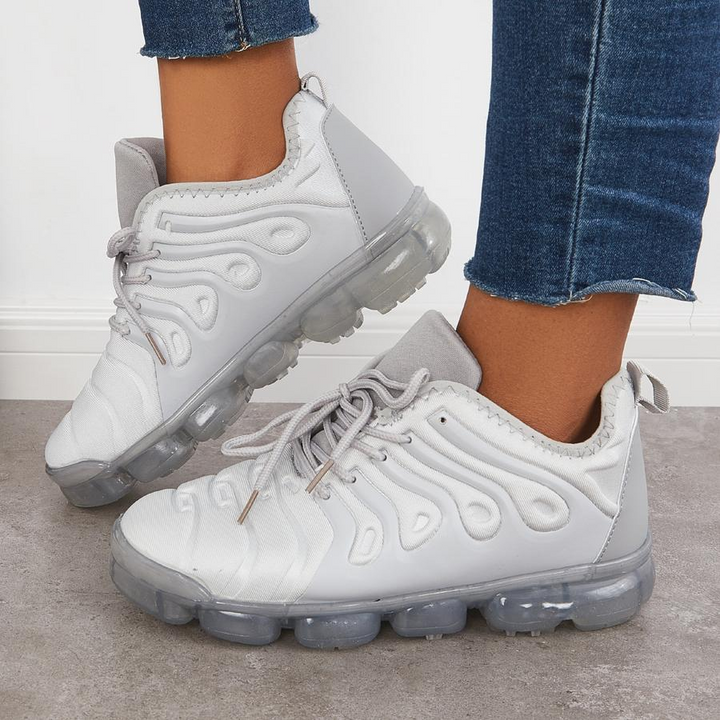 Weiße Sneaker mit transparenten Sohlen, getragen von Person in blauen Jeans. Modische Sportschuhe, ideal für Freizeit und Streetwear.