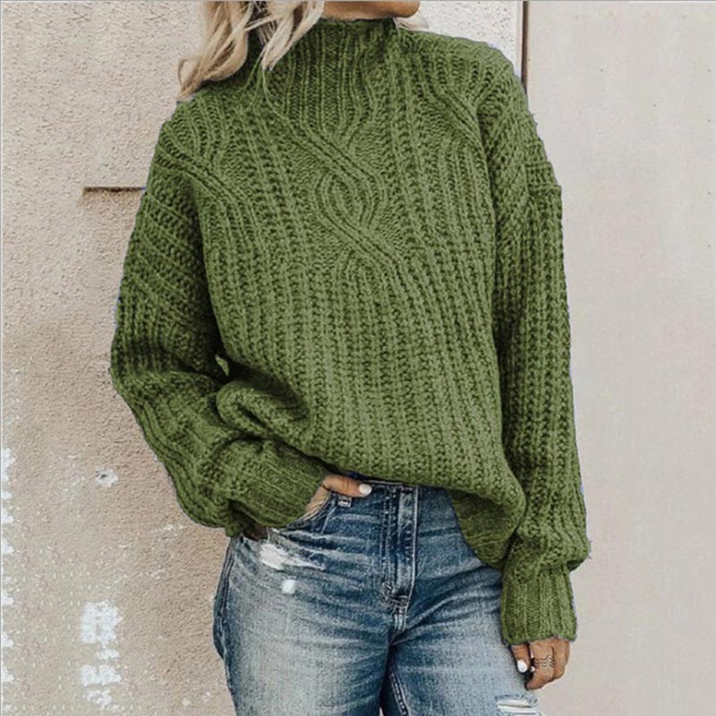 Frau in grünem Strickpullover und zerrissenen Jeans vor beiger Wand. Modetrend, Herbstmode, lässiger Look, Strickmode, Damenbekleidung.