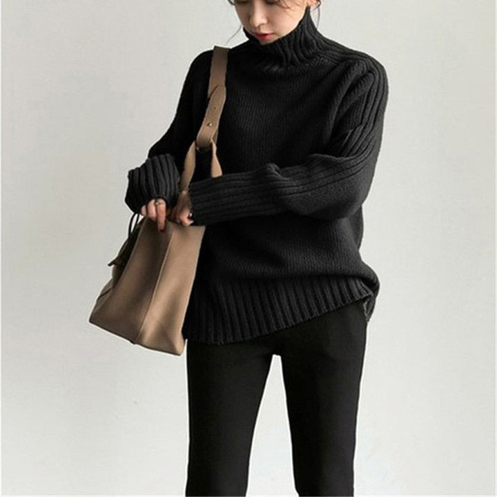 Frau in schwarzem Rollkragenpullover und schwarzer Hose mit beiger Handtasche. Modetrend, Herbstmode, Damenbekleidung, eleganter Look.