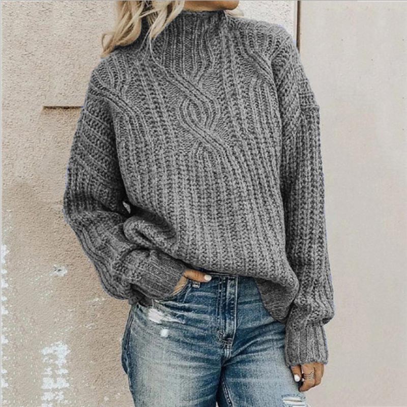 Grauer Strickpullover mit Zopfmuster, getragen von einer Person in blauen Jeans. Modischer Winterlook, gemütlicher Pullover, lässiger Stil.