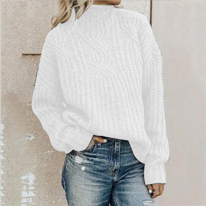 Frau in weißem Strickpullover und zerrissenen Jeans vor beiger Wand. Modetrend, lässiger Herbstlook, Damenmode, Strickmode.