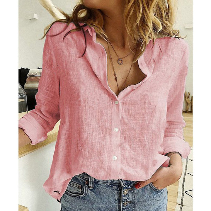 Frau in rosa Leinenbluse und blauer Jeans, lässiger Stil, modische Kleidung, trendiges Outfit, Innenraum, Holzfußboden, natürliche Beleuchtung.