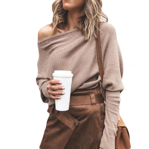 Frau in beigem Off-Shoulder-Pullover und braunem Rock hält Kaffeebecher. Modetrend, Herbstoutfit, Streetstyle, lässige Eleganz.