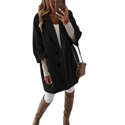 Frau in schwarzem Oversize-Mantel, weißem Outfit und kniehohen Stiefeln, hält Smartphone, modisch, Herbstmode, Streetstyle, eleganter Look.