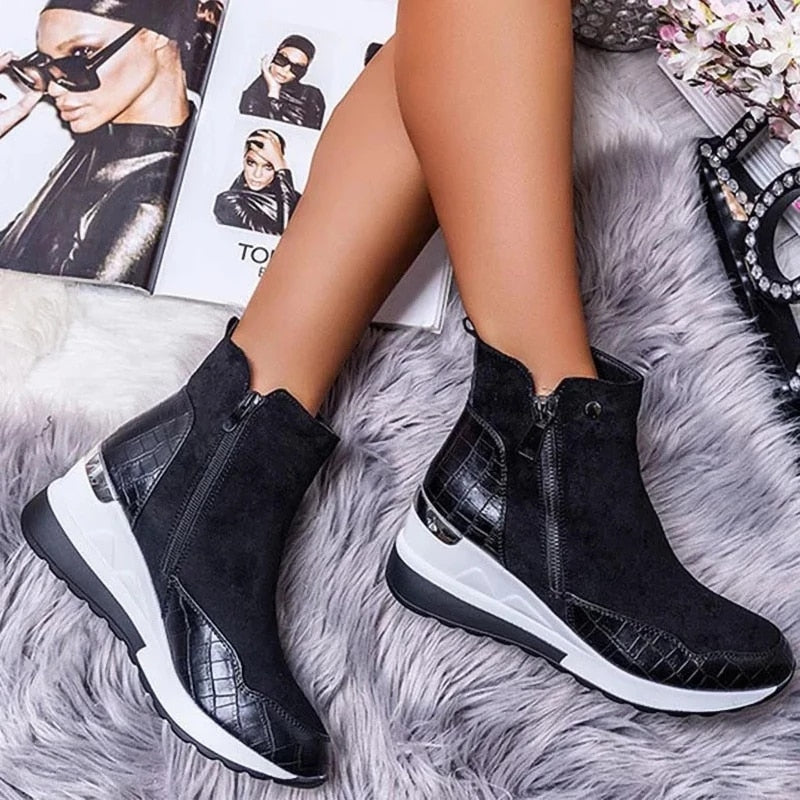 Schwarze Damenstiefeletten mit Reißverschluss und Krokodilleder-Details auf grauem Fellteppich, modisches Schuhdesign, eleganter Look.