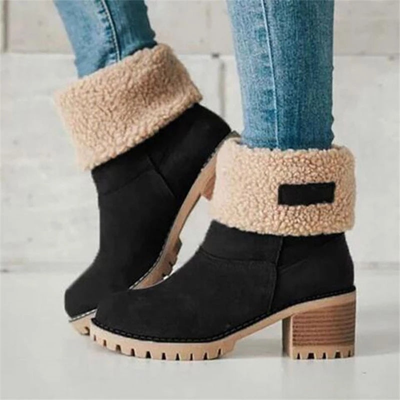 Schwarze Damen-Winterstiefel mit beigem Kunstfell, Blockabsatz und Profilsohle, kombiniert mit blauen Jeans. Ideal für kalte Tage.