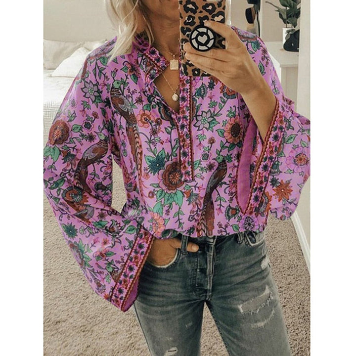 Frau in lila Boho-Bluse mit Blumenmuster, weiten Ärmeln und Jeans, hält ein Smartphone mit Leopardenhülle. Trendige Mode, Boho-Stil.