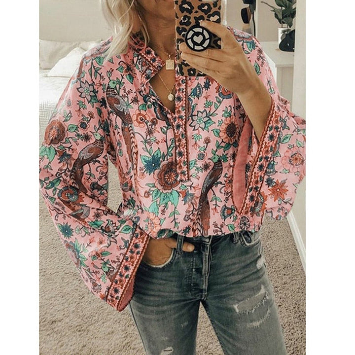 Frau in geblümter Bluse mit weiten Ärmeln, hält Smartphone mit Leopardenmuster-Hülle, trägt Jeans, modisches Outfit, Selfie im Spiegel.