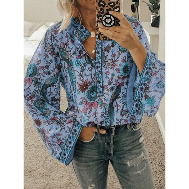 Frau in blauer, geblümter Bluse mit langen Ärmeln und zerrissener Jeans, hält Smartphone mit Leopardenmuster-Hülle. Trendige Damenmode, Freizeitlook.