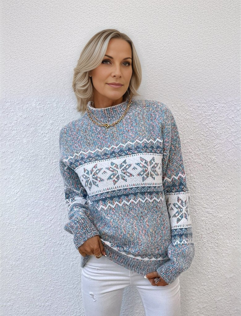 Frau in grauem Strickpullover mit Schneeflockenmuster, weiße Jeans, lässiger Winterlook, Mode für kalte Tage, stilvolle Damenbekleidung.