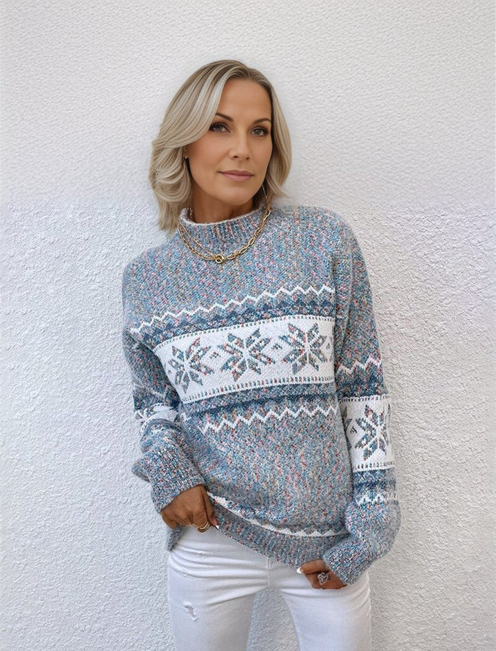 Frau in grauem Strickpullover mit Schneeflockenmuster, weiße Jeans, lässiger Winterlook, Mode für kalte Tage, stilvolle Damenbekleidung.