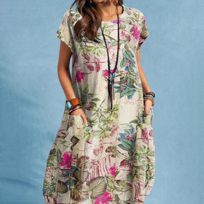 Frau in geblümtem Sommerkleid mit Taschen vor blauem Hintergrund, trägt lange Halskette und Armbänder. Boho-Chic, lässige Mode.