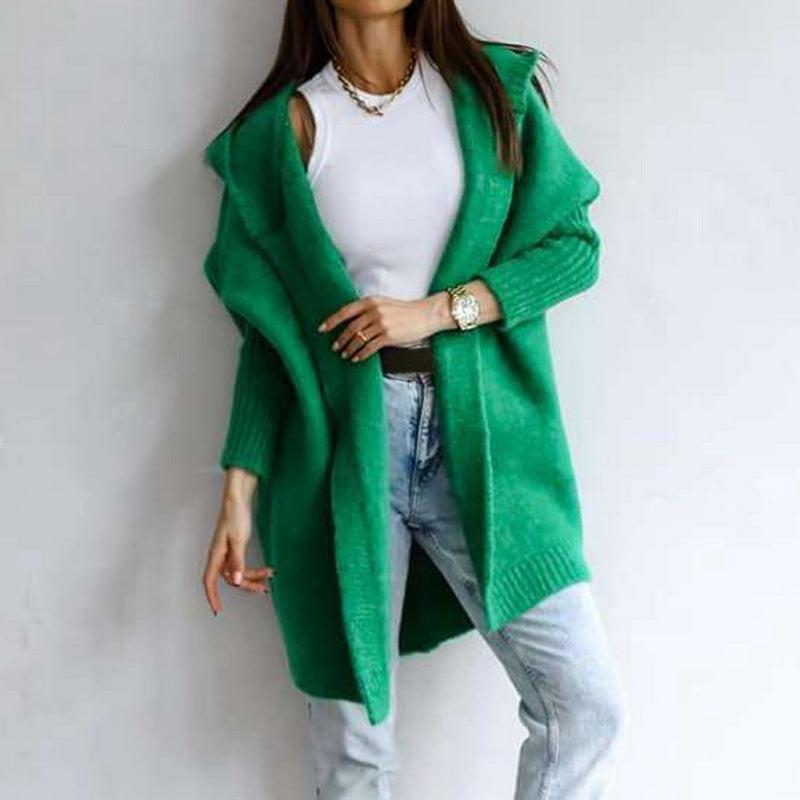 Frau in grünem Strick-Cardigan, weißem Top und Jeans. Modetrend, lässiger Stil, Herbstmode, Damenbekleidung, gemütlicher Look.