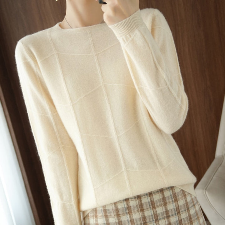 Damenpullover aus cremefarbenem Strick mit geometrischem Muster, kombiniert mit kariertem Rock. Elegante Herbstmode, stilvoll und gemütlich.