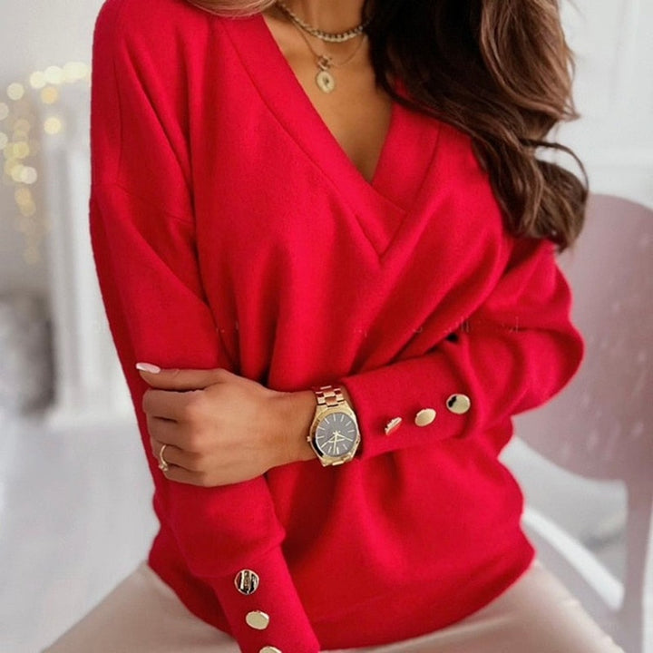 Frau in rotem Pullover mit V-Ausschnitt und goldenen Knöpfen, trägt eine elegante Uhr und Halskette. Modetrend, Damenmode, stilvoller Look.