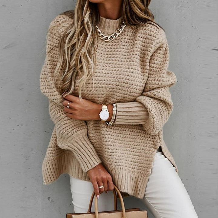 Beige Strickpullover Damenmode, kombiniert mit weißer Hose und goldener Kette. Trendiger Herbstlook, eleganter Stil, modisches Outfit.