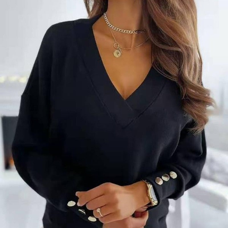 Frau in schwarzem V-Ausschnitt-Pullover mit Knöpfen, trägt goldene Halskette und Armbanduhr. Elegante Damenmode, stilvolles Outfit.