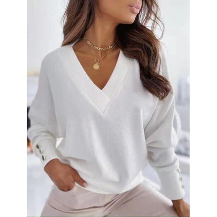 Weiße Damenbluse mit V-Ausschnitt und Knopfleiste an den Ärmeln, kombiniert mit goldener Halskette. Elegante Mode für Frauen, stilvoll und modern.