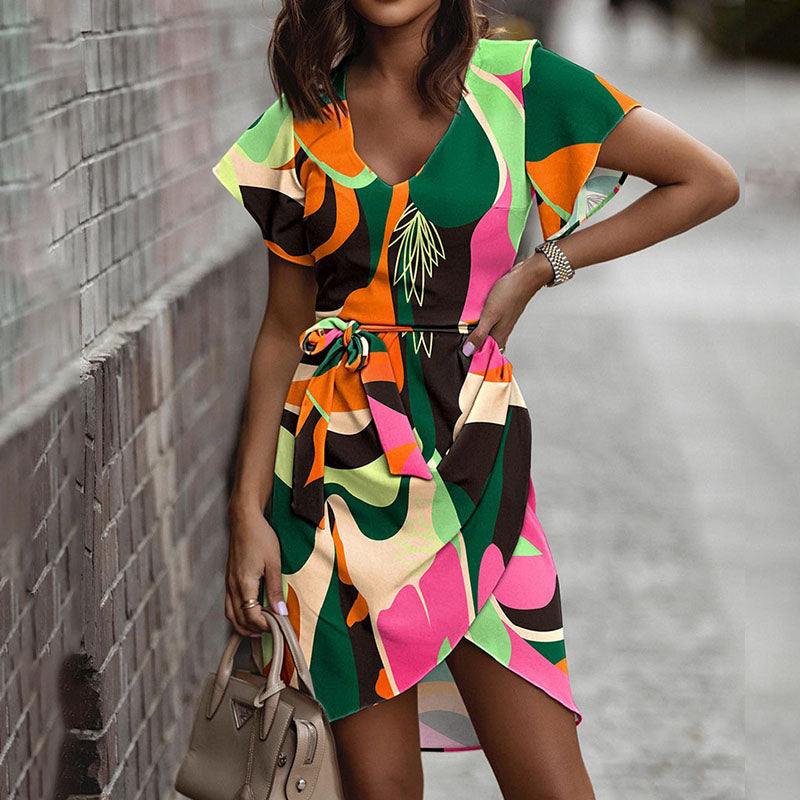 Frau in buntem, geometrisch gemustertem Sommerkleid mit Gürtel, hält beigefarbene Handtasche. Modetrend, Damenmode, Streetstyle.