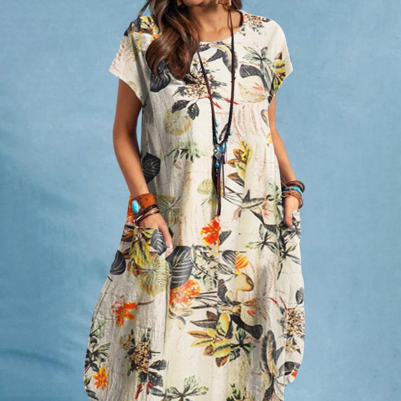 Frau in geblümtem Sommerkleid vor blauem Hintergrund, trägt lange Halskette und Armbänder. Modetrend, Damenmode, lässiger Stil.