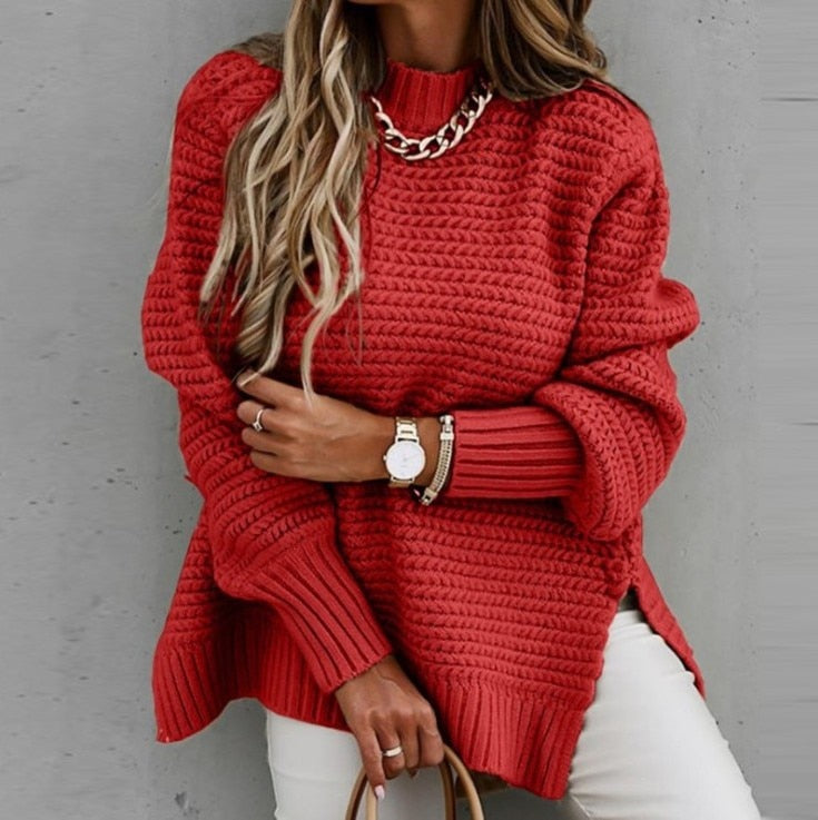 Frau in rotem Strickpullover mit Kettendetail, trägt Armbanduhr und weiße Hose. Modetrend Herbst, stilvoller Look, lässige Eleganz.