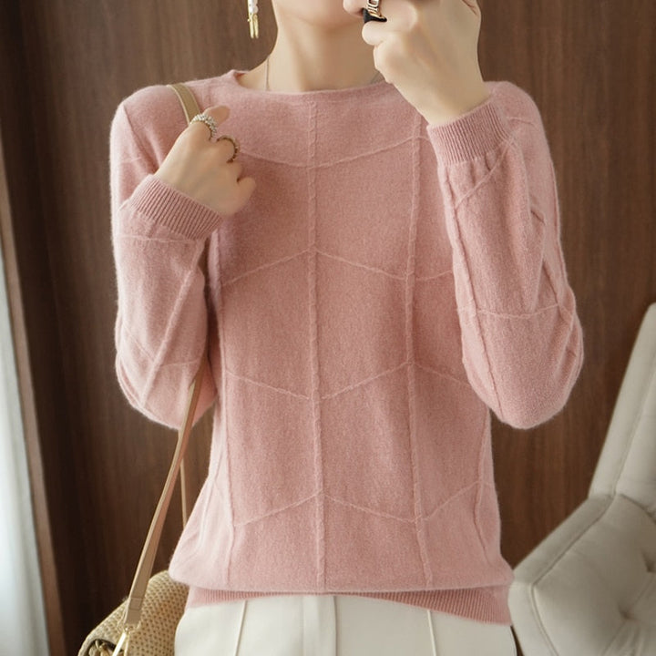 Dame in rosa Strickpullover mit geometrischem Muster, hält eine Handtasche. Modischer Herbst-Look, elegantes Design, weiches Material.
