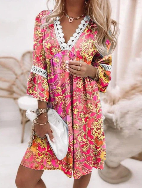 Frau in farbenfrohem, geblümtem Kleid mit Spitzenbesatz, hält weiße Clutch. Sommermode, Boho-Stil, modisches Outfit, trendige Damenbekleidung.