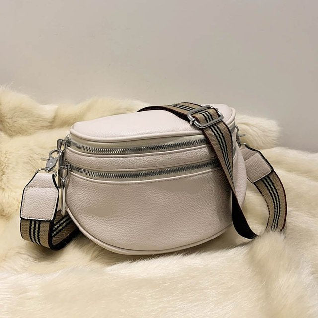 Weiße Leder-Bauchtasche mit gestreiftem Schultergurt auf Fellunterlage. Modische Umhängetasche, ideal für Damen, stilvoll und praktisch.