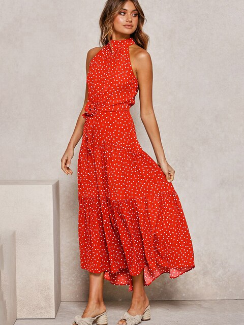 Frau in rotem, gepunktetem Maxikleid vor grauem Hintergrund, modisch, elegant, Sommerkleid, Damenmode, trendiges Outfit, stilvoll, feminin.