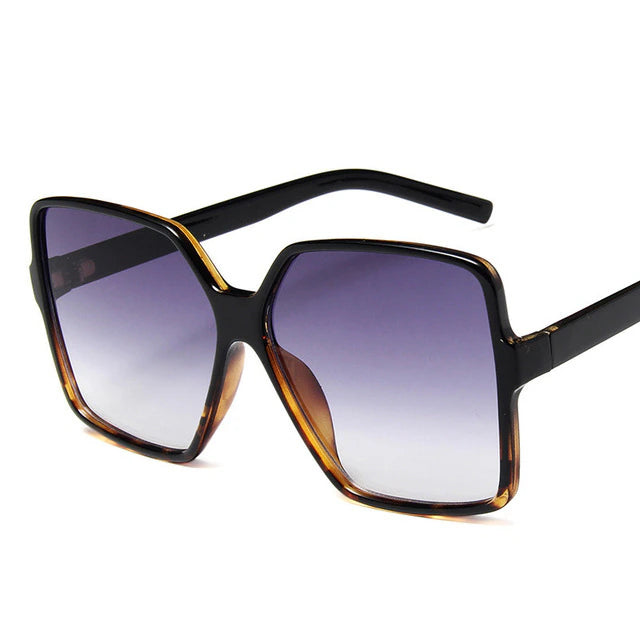 Schwarze übergroße Sonnenbrille mit eckigem Rahmen und lila getönten Gläsern, modisches Accessoire, UV-Schutz, Damenmode.