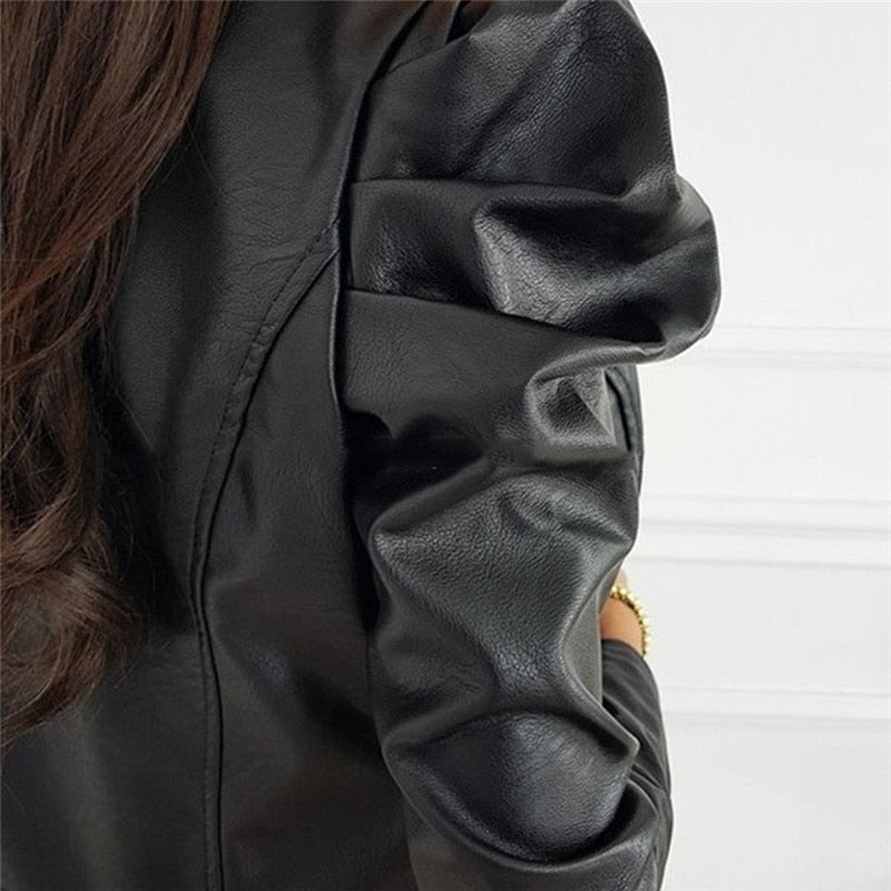 Nahaufnahme einer schwarzen Lederjacke mit modischen Puffärmeln, getragen von einer Person mit langen, dunklen Haaren. Elegante Damenmode.