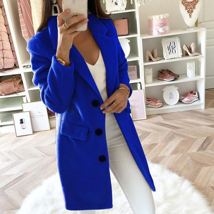 Frau in blauem Mantel, weißem Outfit, macht Selfie in modernem Ankleidezimmer. Mode, Damenbekleidung, stilvolle Wintermode.