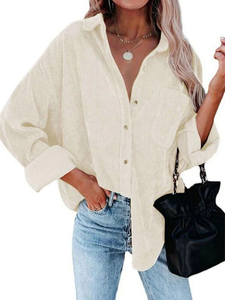 Frau in beiger Cordbluse, lässig geknöpft, kombiniert mit blauer Jeans und schwarzer Tasche. Modetrend, Freizeitlook, Damenmode.