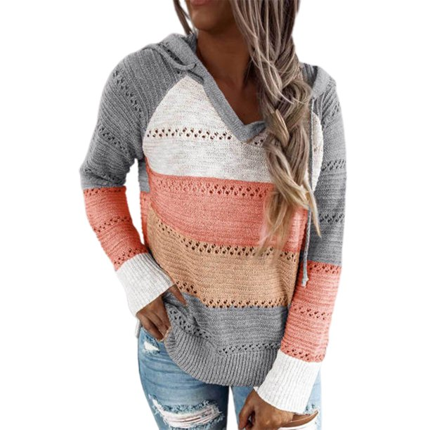Frau trägt gestreiften Strickpullover in Grau, Weiß, Orange und Rosa mit Kapuze. Modischer Damenpullover, ideal für Herbst und Winter.