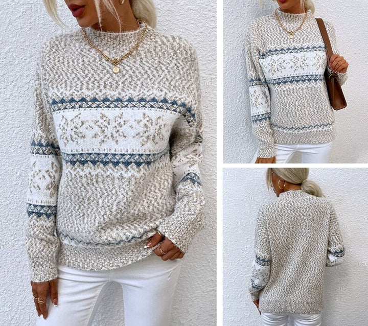 Frau trägt beige Strickpullover mit blau-weißem Norwegermuster, kombiniert mit weißen Hosen. Modischer Winterlook, gemütlicher Strickstil.