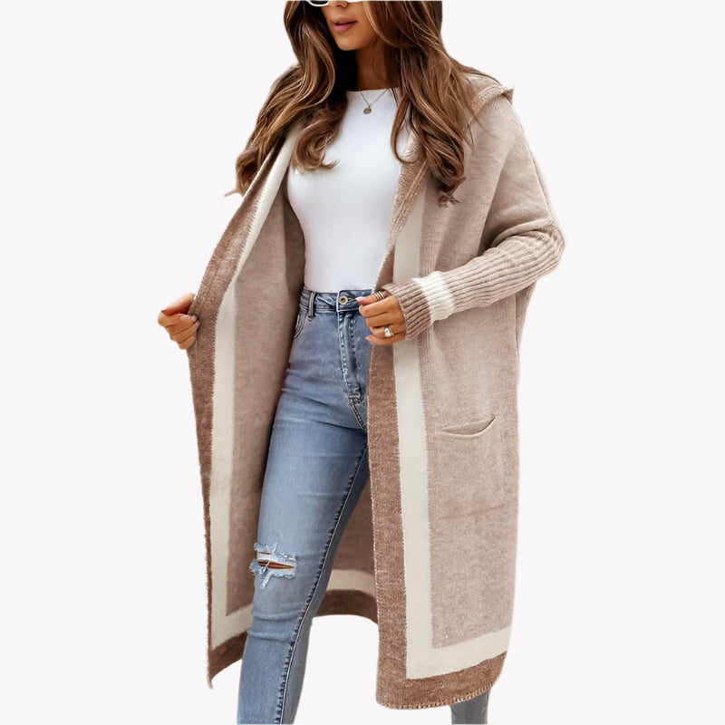Frau in modischer langer Strickjacke, weißem Top und blauen Jeans. Stilvolle Herbstmode, lässiger Look, weißer Studiohintergrund.