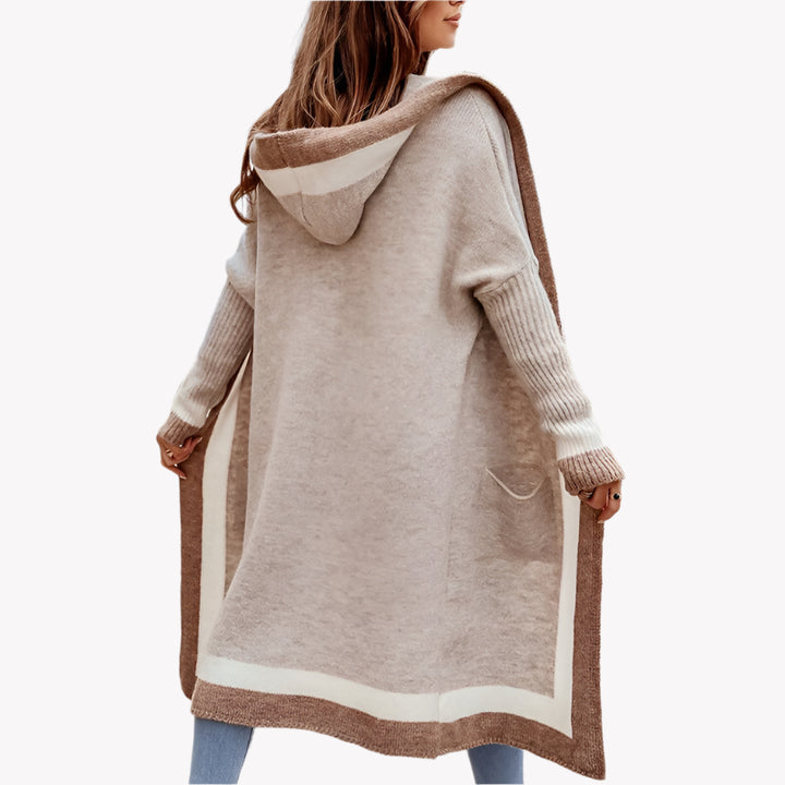 Frau in beigem Strickmantel mit Kapuze, lässig vor einem weißen Hintergrund. Herbstmode-Trend, gemütlicher Look, stilvolle Frauenkleidung, Outdoor-Mode.
