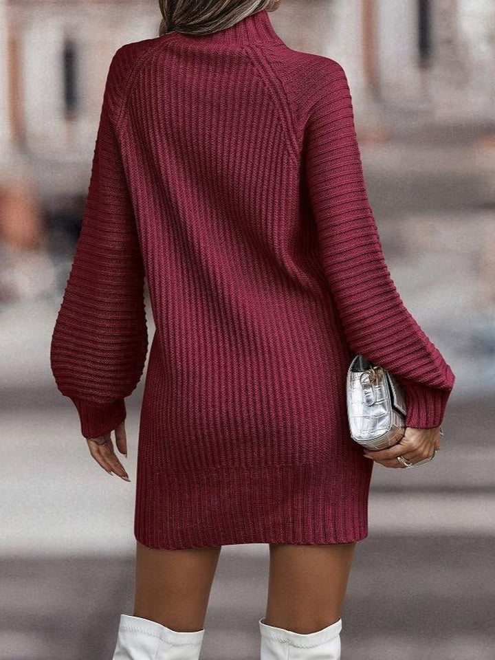 Frau in rotem Strickkleid mit langen Ärmeln, hält silberne Clutch, trägt weiße Stiefel. Modetrend Herbst, eleganter Look, Streetstyle.