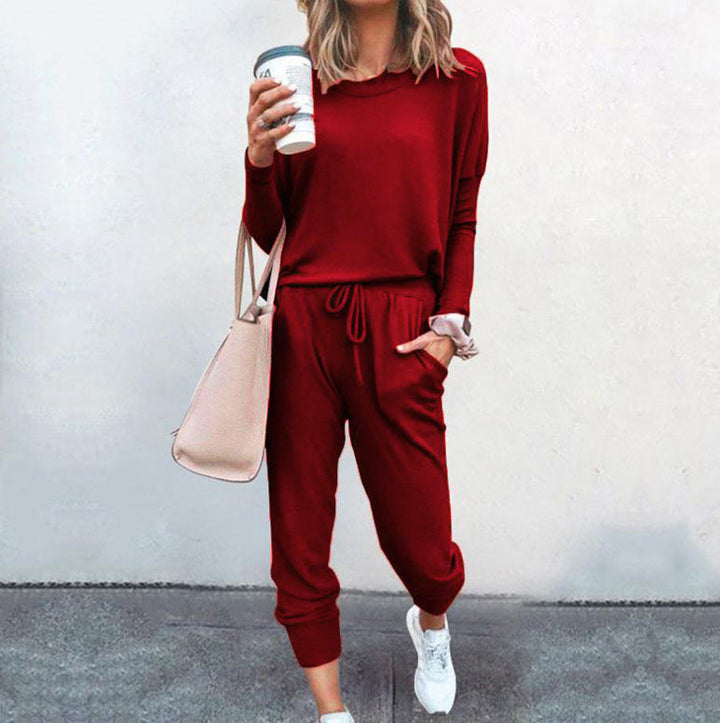 Frau in rotem Freizeitanzug mit Kaffeebecher und Handtasche, lässiger Streetstyle, weiße Sneaker, modisch und bequem, urbaner Look.