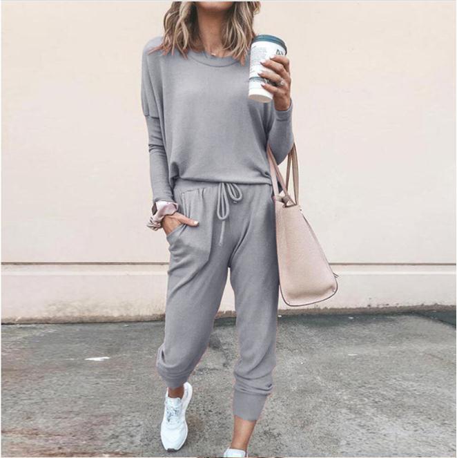 Frau in grauem Jogginganzug mit Kaffeebecher und beiger Handtasche, lässiger Streetstyle, Mode für Damen, bequeme Freizeitkleidung.